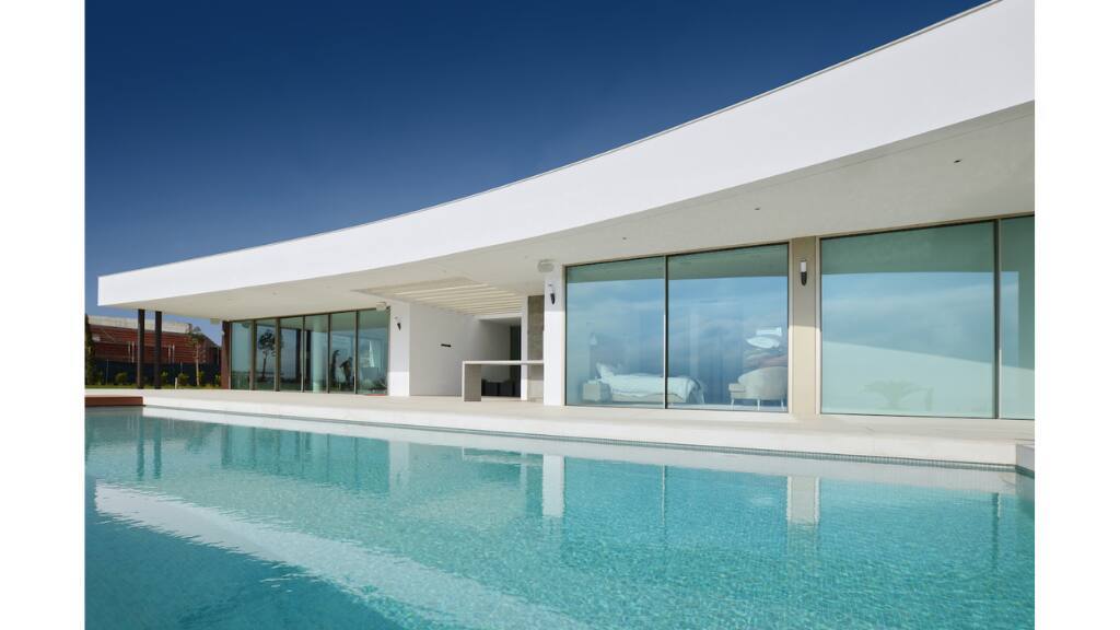 Lote 21, Alma do Mar, Lagos - the finished villa from the pool, with the full-height glazing and lighting design that won the Control4 award