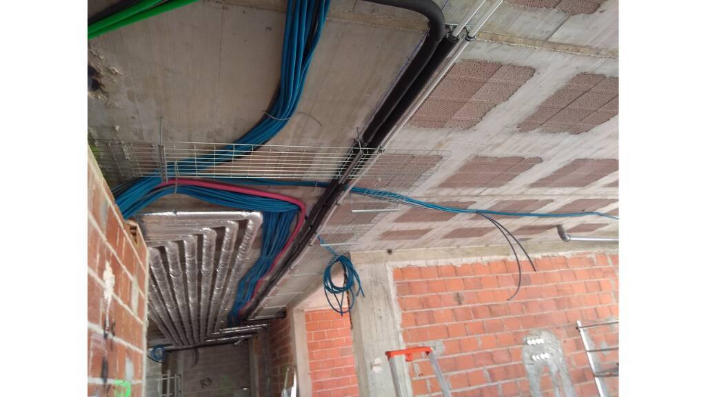 Lote 21, Alma do Mar - electrical conduit and cable tray routed under the slab before the ceiling was closed, first-fix stage of the iHome installation